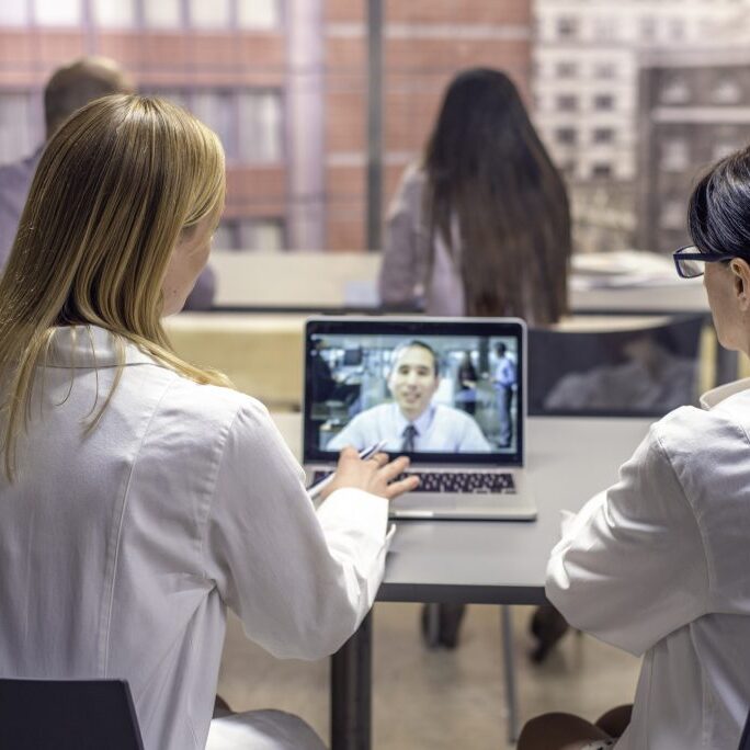 Two female doctors having video conference with  colleague.
